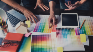 Mãos de pessoas tocando em paletas de cores que estão em cima de uma mesa